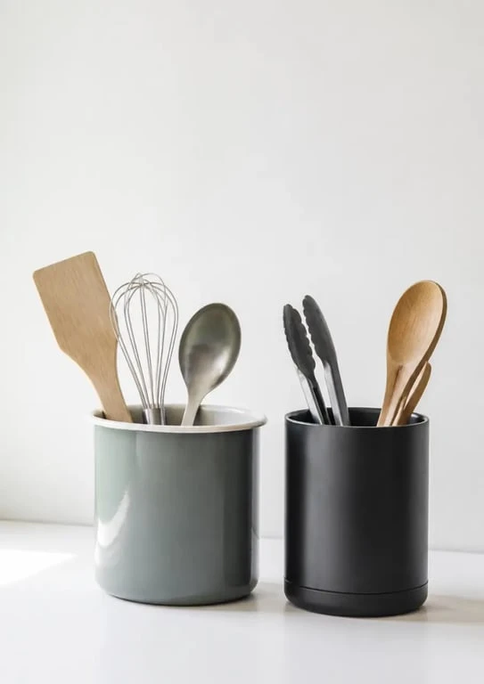 Deux pots pour ustensiles de cuisine sur un plan de travail, style rétro et contemporain
